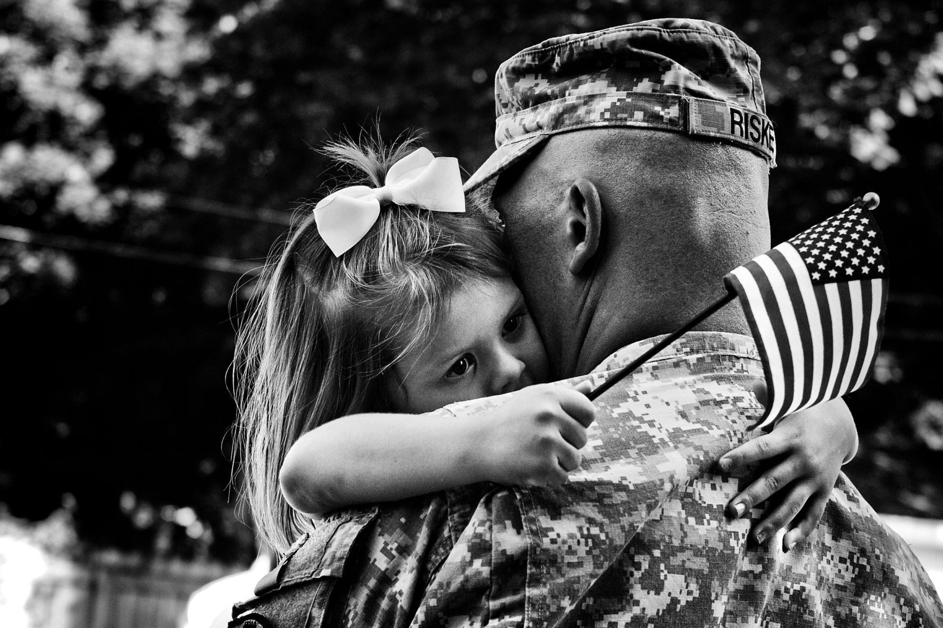 A young girl hugs her father in a yard